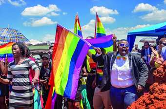 A colour photo of a group of people waving rainbow flags