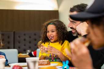 A family smiling and having drinks and food in the café at Tate Britain