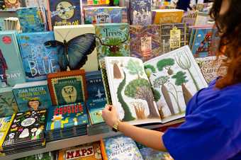 A visitor browsing children's books in the Turbine Hall shop at Tate Modern