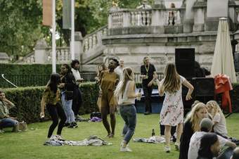 A group of people dancing on the grass outside Tate Britain