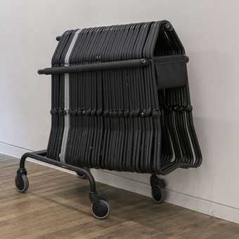 A stack of foldable stools next to the gallery wall. 