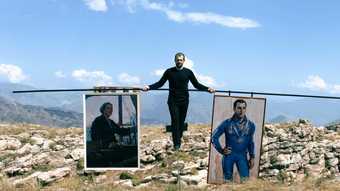 Man walking on a tightrope holding a balance pole with a painting hanging on either end.