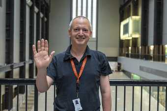 A visitor experience staff member smiles and waves at the camera